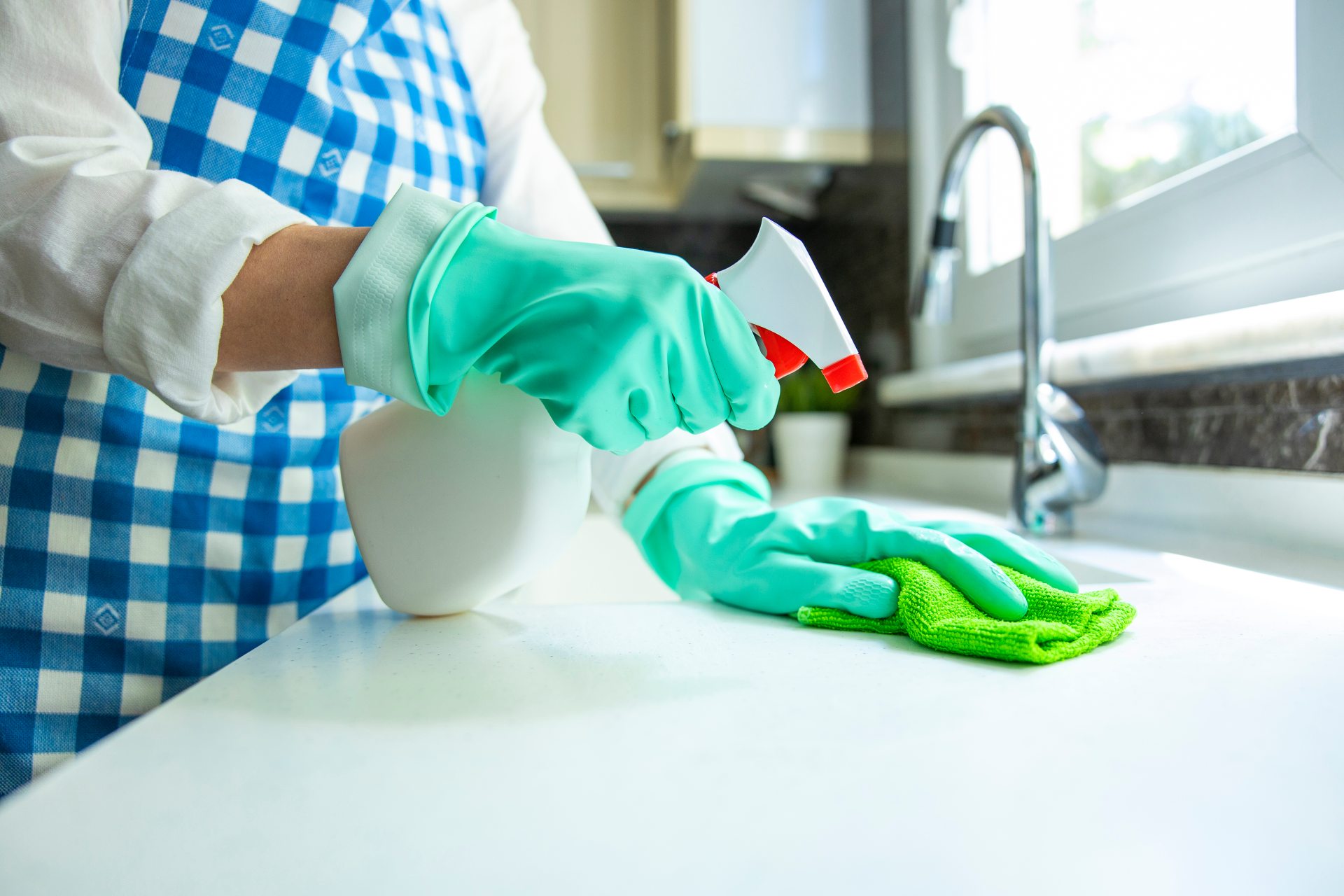 Person wearing gloves cleaning a countertop